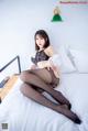 A woman sitting on top of a bed wearing black stockings.