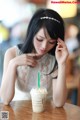 A woman sitting at a table with a drink in her hand.