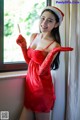 A woman in a red dress and a santa hat holding a knife.