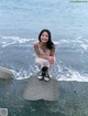 A woman sitting on a rock by the ocean.