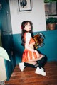 A woman in an orange and white cheerleader outfit posing for a picture.