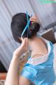 A woman in a blue dress is putting on her hair.