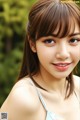 A young woman with long brown hair and bangs smiles at the camera.