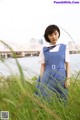 A woman in a blue dress standing in tall grass.