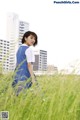 A woman in a blue dress standing in tall grass.