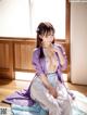 A woman in a purple kimono sitting on a bed.