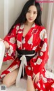 A woman in a red kimono sitting on a white rug.