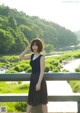 A woman standing on a bridge next to a river.