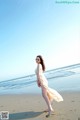 A woman in a white dress standing on a beach.