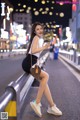 A woman sitting on a railing eating an ice cream cone.