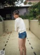 A woman in a white shirt and blue shorts posing for a picture.