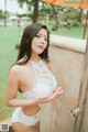 A woman in a white lingerie standing next to a shower.