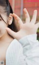 A woman in a white shirt is making a peace sign with her hand.