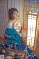 A woman in a blue kimono sitting on a table.