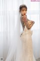 A woman in a wedding dress with a tattoo on her arm.