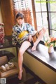 A woman in a kimono sitting on a window sill.