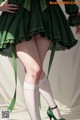 A woman in a green dress and white stockings.